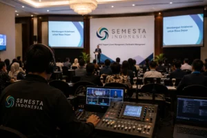Conference support Semesta Indonesia dengan tim teknis, peserta, pembicara, dan layar presentasi dalam forum formal.